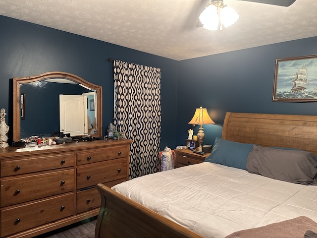 bedroom with ceiling fan, hardwood / wood-style floors, and a textured ceiling