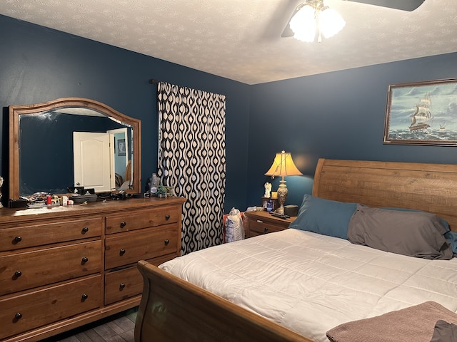 bedroom with a textured ceiling, ceiling fan, and dark wood-type flooring