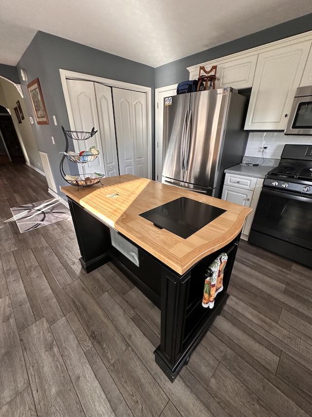 kitchen featuring white cabinets, appliances with stainless steel finishes, dark hardwood / wood-style floors, and tasteful backsplash