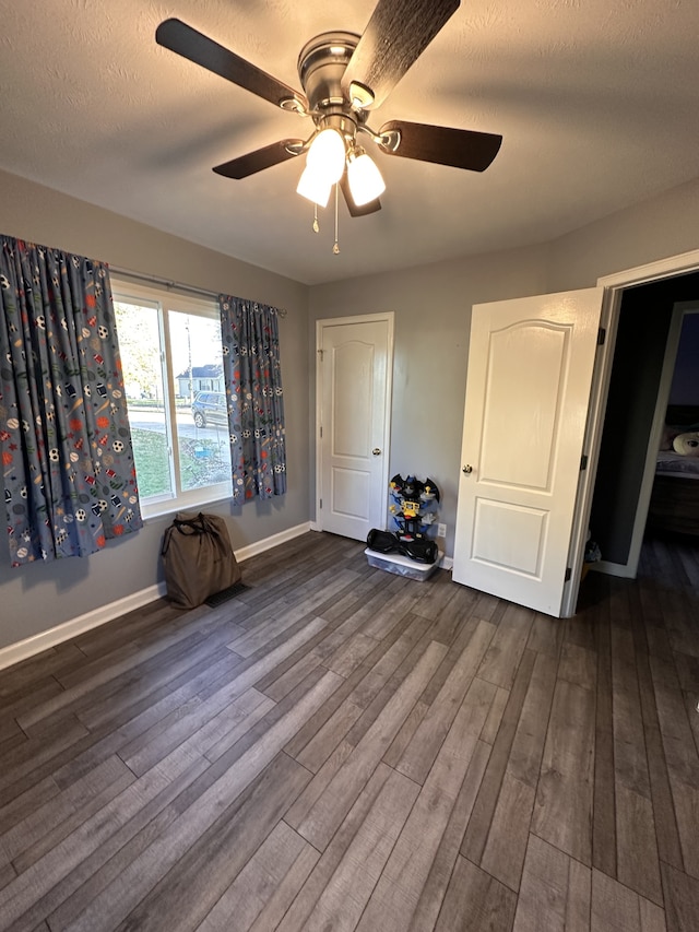 unfurnished bedroom with a textured ceiling, ceiling fan, and dark hardwood / wood-style floors