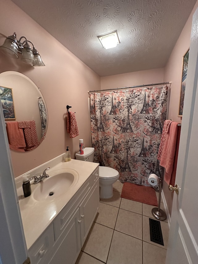 bathroom with tile patterned floors, vanity, a textured ceiling, and toilet