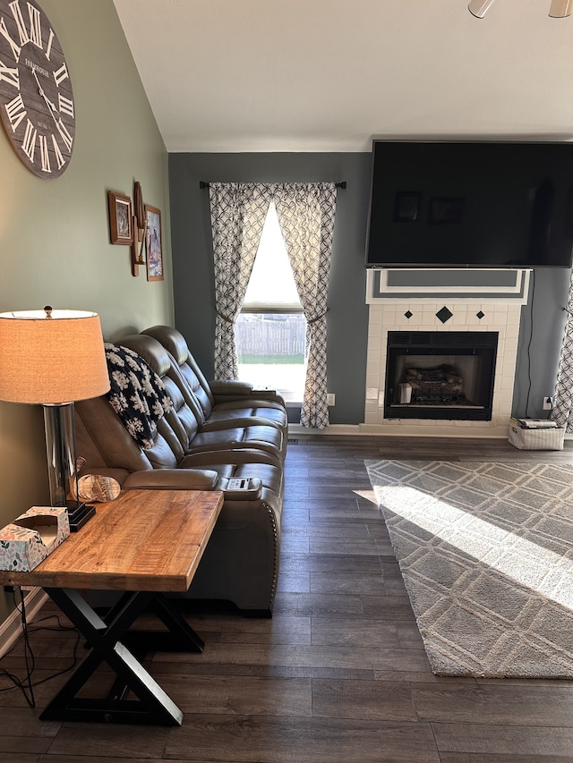 living room featuring dark hardwood / wood-style floors, a tile fireplace, and vaulted ceiling