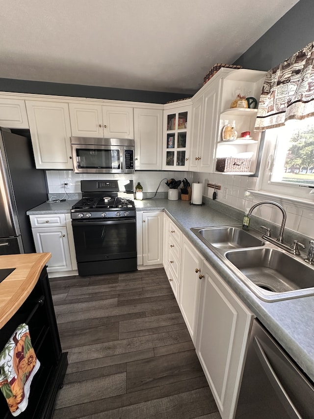 kitchen with tasteful backsplash, stainless steel appliances, sink, dark hardwood / wood-style floors, and white cabinetry