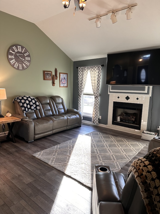 living room with a tile fireplace, rail lighting, wood-type flooring, and lofted ceiling