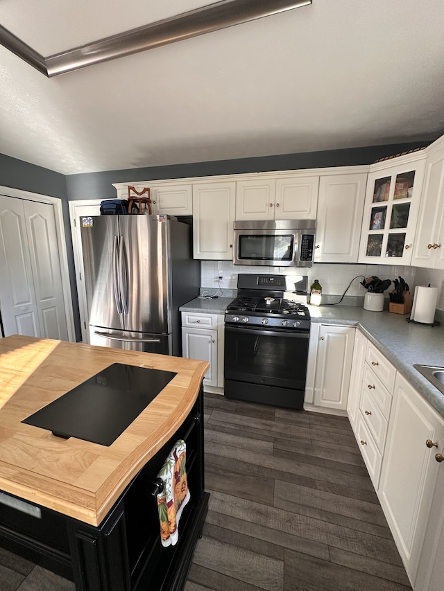 kitchen with decorative backsplash, white cabinetry, stainless steel appliances, and dark wood-type flooring