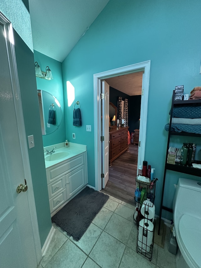 bathroom with wood-type flooring, vanity, toilet, and lofted ceiling