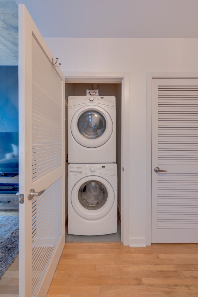 clothes washing area featuring light hardwood / wood-style floors and stacked washer / drying machine