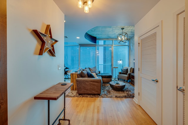 living room with a wall of windows, an inviting chandelier, and light wood-type flooring