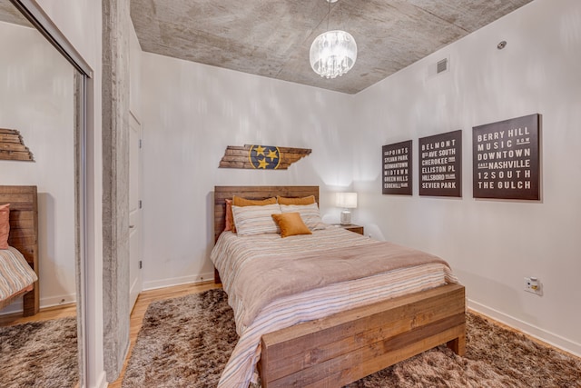 bedroom featuring wood-type flooring, a notable chandelier, and a closet