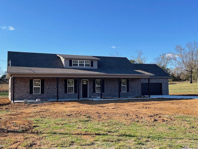 view of front of property with a front yard, a porch, and a garage