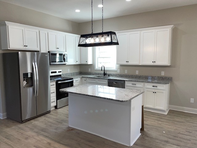 kitchen featuring stainless steel appliances, a kitchen island, white cabinetry, and sink