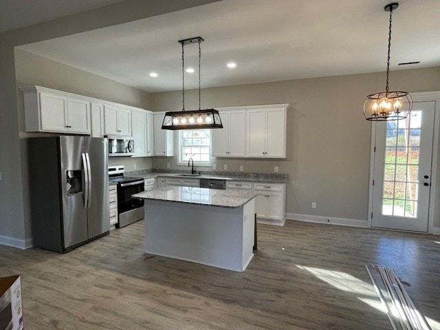 kitchen with white cabinets, a kitchen island, stainless steel appliances, and pendant lighting