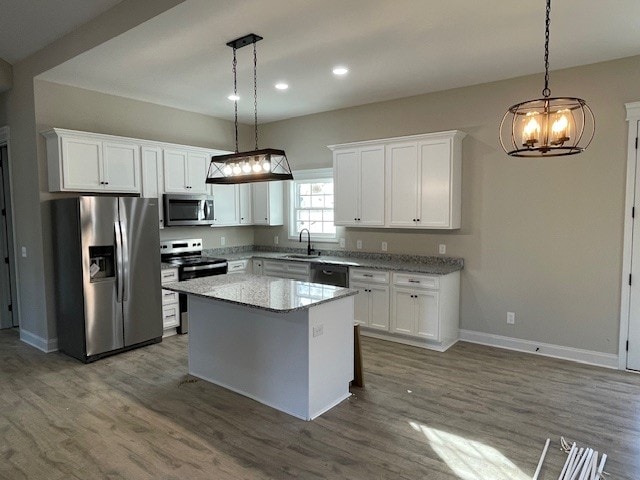 kitchen with white cabinetry, hanging light fixtures, a kitchen island, and stainless steel appliances