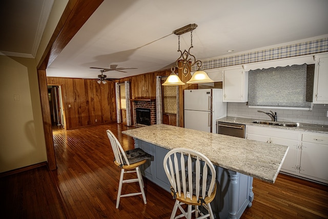 kitchen featuring a kitchen bar, white refrigerator, and white cabinetry