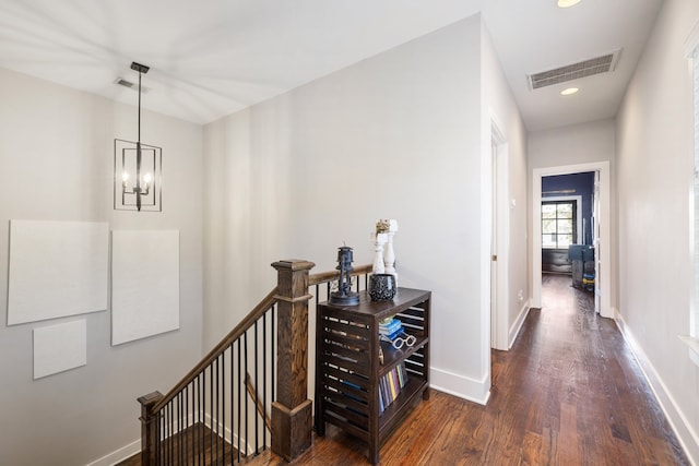 hallway with dark hardwood / wood-style floors and a chandelier