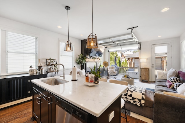 kitchen with an island with sink, dark hardwood / wood-style floors, sink, pendant lighting, and dishwasher