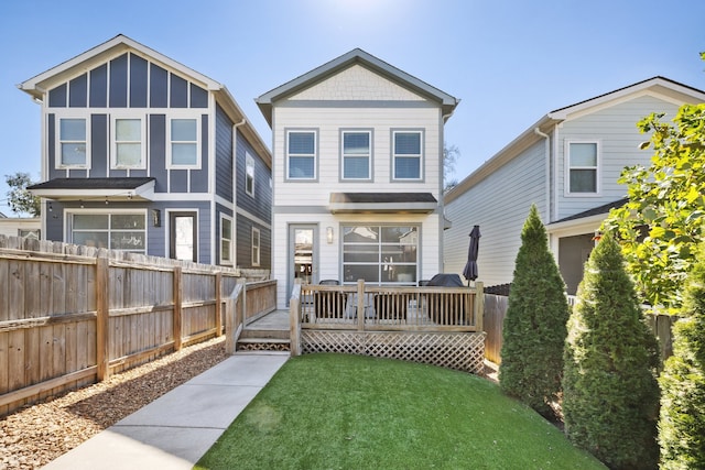 back of property with a wooden deck and a yard