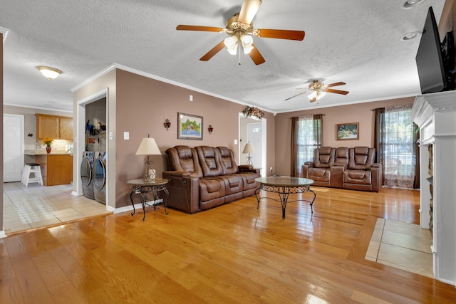 living room featuring ceiling fan, light wood-type flooring, crown molding, and independent washer and dryer