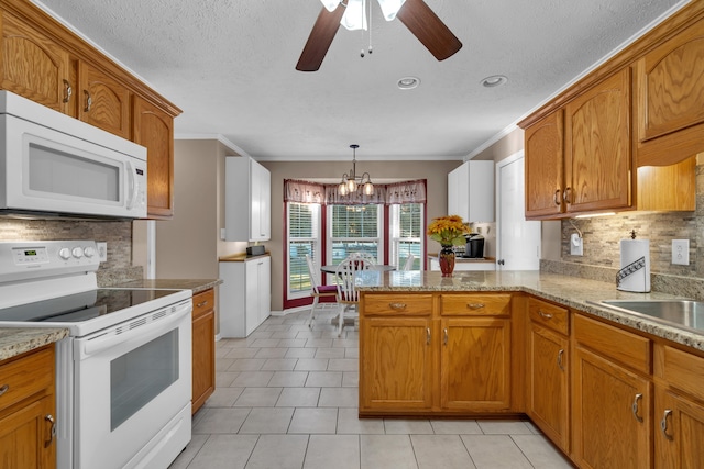 kitchen with kitchen peninsula, pendant lighting, crown molding, and white appliances