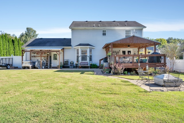 rear view of house featuring ceiling fan, a deck, a lawn, and a patio area