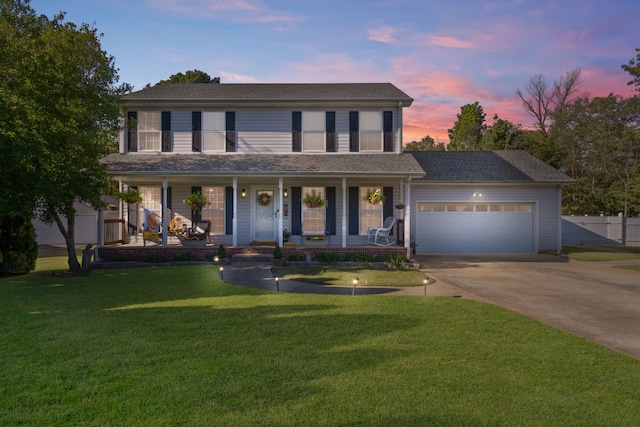 view of front facade with a yard, covered porch, and a garage