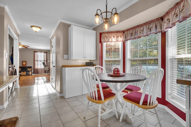 tiled dining space with ornamental molding, a wealth of natural light, ceiling fan with notable chandelier, and a textured ceiling