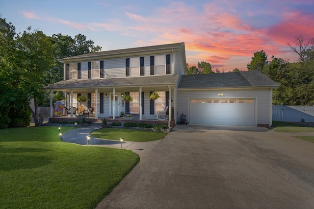 colonial-style house featuring a garage, a lawn, and covered porch