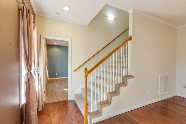 stairway featuring ornamental molding and wood-type flooring