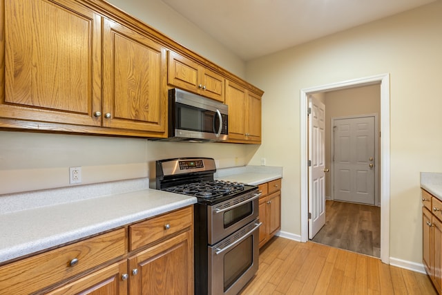 kitchen with light hardwood / wood-style floors and appliances with stainless steel finishes