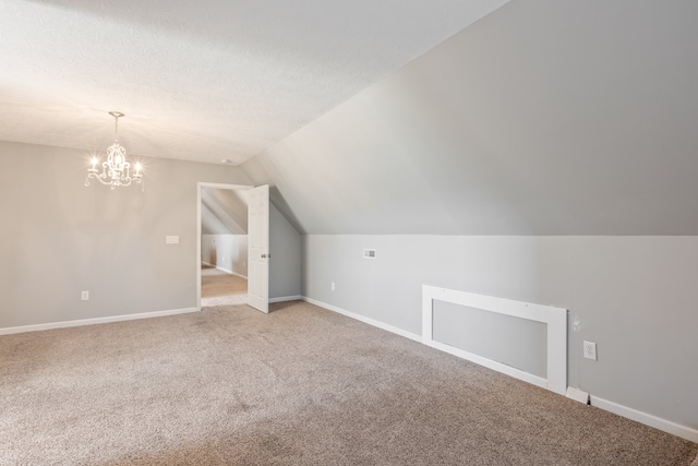 bonus room featuring carpet, vaulted ceiling, a notable chandelier, and a textured ceiling