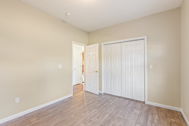 unfurnished bedroom with a closet and light wood-type flooring