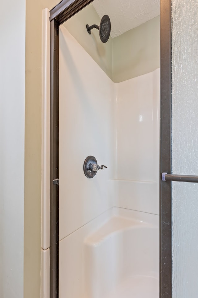 bathroom with a shower and a textured ceiling