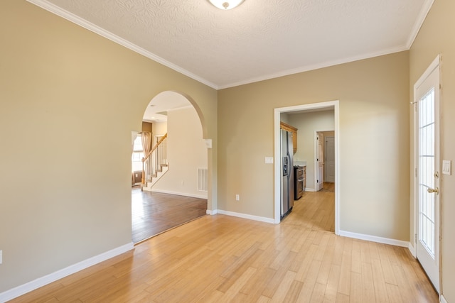 unfurnished room with a textured ceiling, a healthy amount of sunlight, and light wood-type flooring