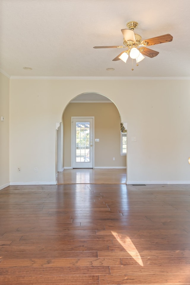 empty room with dark wood-type flooring, crown molding, and ceiling fan