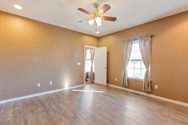 spare room with ceiling fan, a textured ceiling, and light wood-type flooring