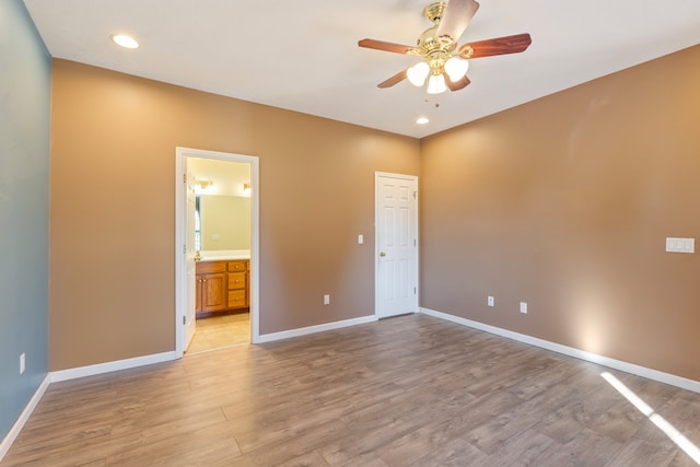 unfurnished bedroom with ensuite bathroom, light wood-type flooring, and ceiling fan