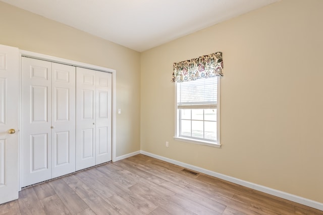 unfurnished bedroom with a closet and light wood-type flooring