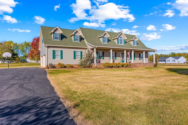 new england style home with covered porch, a garage, and a front lawn