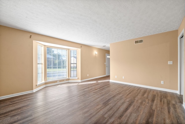 empty room featuring dark hardwood / wood-style floors and a textured ceiling