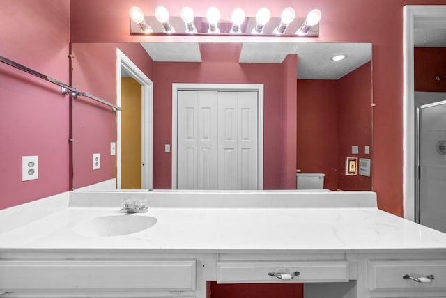 bathroom with vanity, toilet, and a shower with door