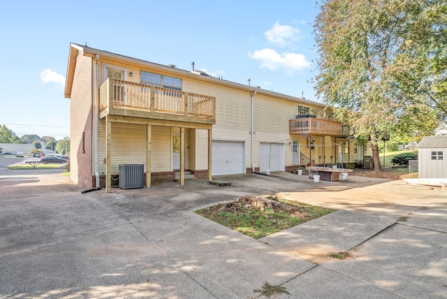 back of house with central air condition unit, a balcony, and a garage