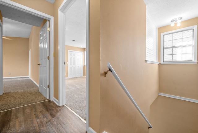 stairway with a textured ceiling and wood-type flooring