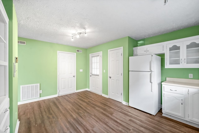 kitchen featuring white cabinetry, a textured ceiling, hardwood / wood-style floors, and white refrigerator