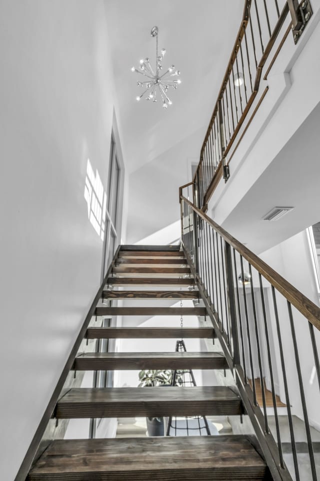 staircase with a high ceiling and a chandelier