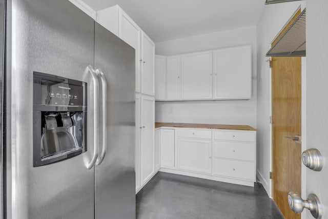 kitchen with white cabinets, stainless steel fridge, and butcher block countertops