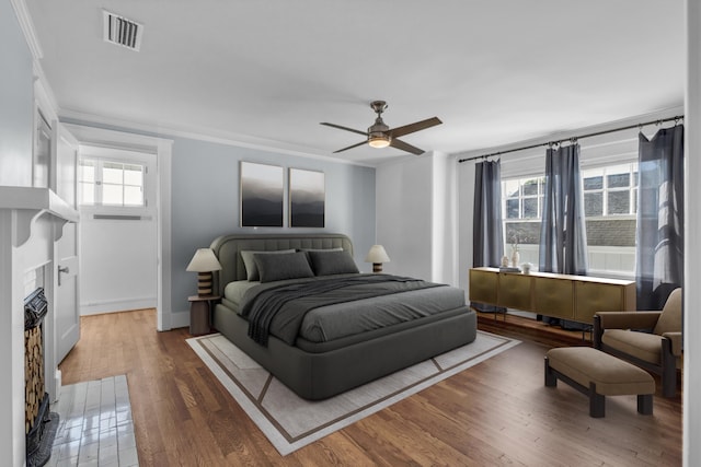 bedroom with ornamental molding, hardwood / wood-style floors, multiple windows, and ceiling fan