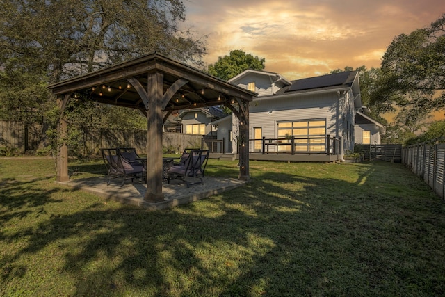 back house at dusk featuring a gazebo, a patio, and a yard