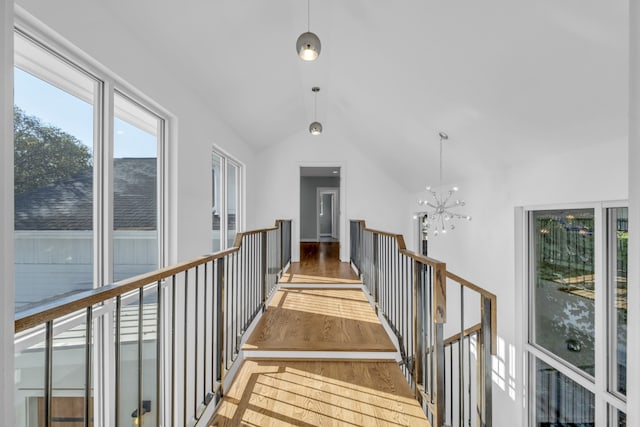 corridor featuring vaulted ceiling, an inviting chandelier, and hardwood / wood-style floors