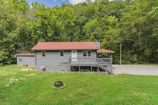 view of front of house with a front yard, a deck, and an outdoor fire pit