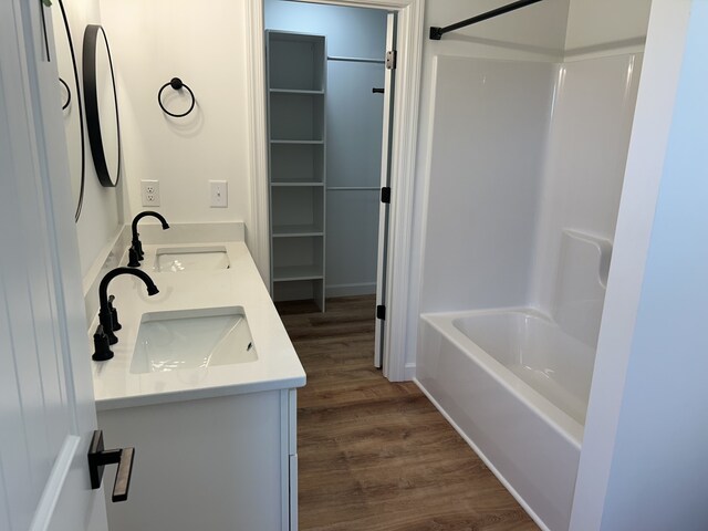 bathroom with shower / bathing tub combination, wood-type flooring, and vanity